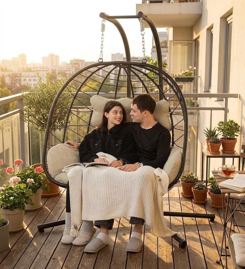 Two adults seated in the DoubleTT Double Egg Chair Loveseat on a patio